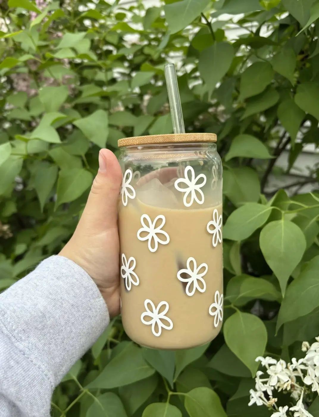 Clear glass flower glass mug with white floral decals bamboo lid filled with iced coffee botanical flower glass