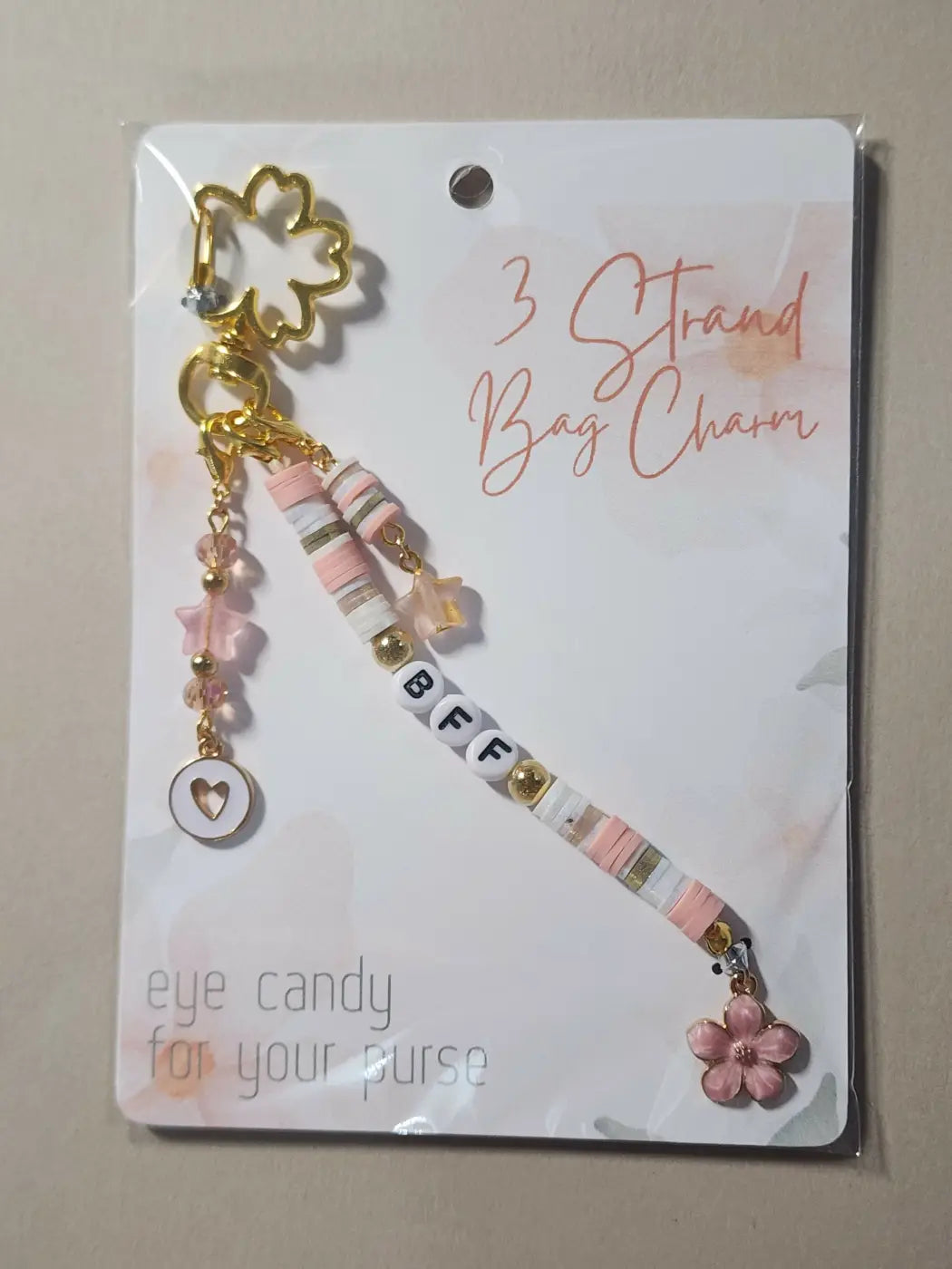 Charm 2 is a delicate gold-toned bag charm with pink and white striped beads, crystal accents, star charms, and flower detail