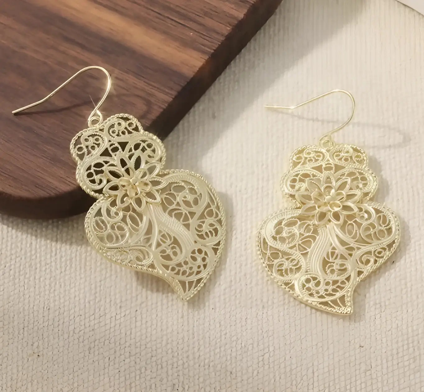 Delicate gold-toned filigree earrings with intricate lace-like patterns and a vintage hollow carved heart design