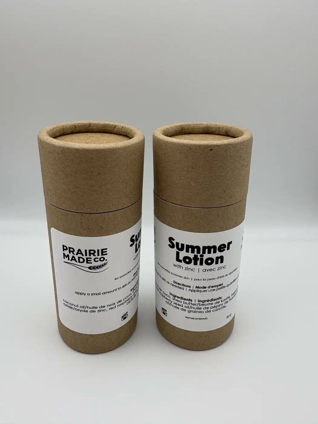Two cylindrical brown cardboard tubes of prairie made summer lotion with zinc featuring natural skincare canada label