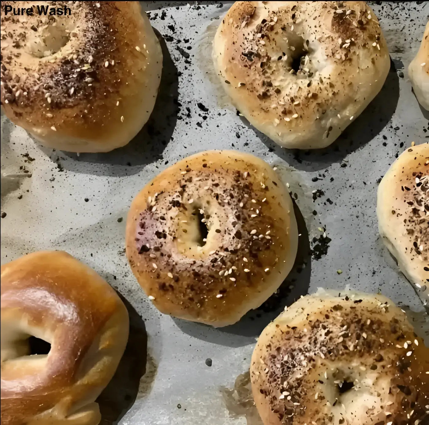 Golden-brown freshly baked sourdough bagels with glossy finish topped with sesame seeds in pre-order variety pack