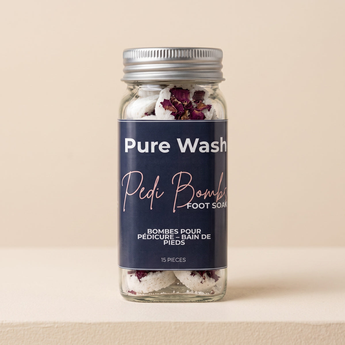 Pure Wash Pedi Bombs in a clear glass jar with dried rose petals for a relaxing spa-inspired foot soak at home.
