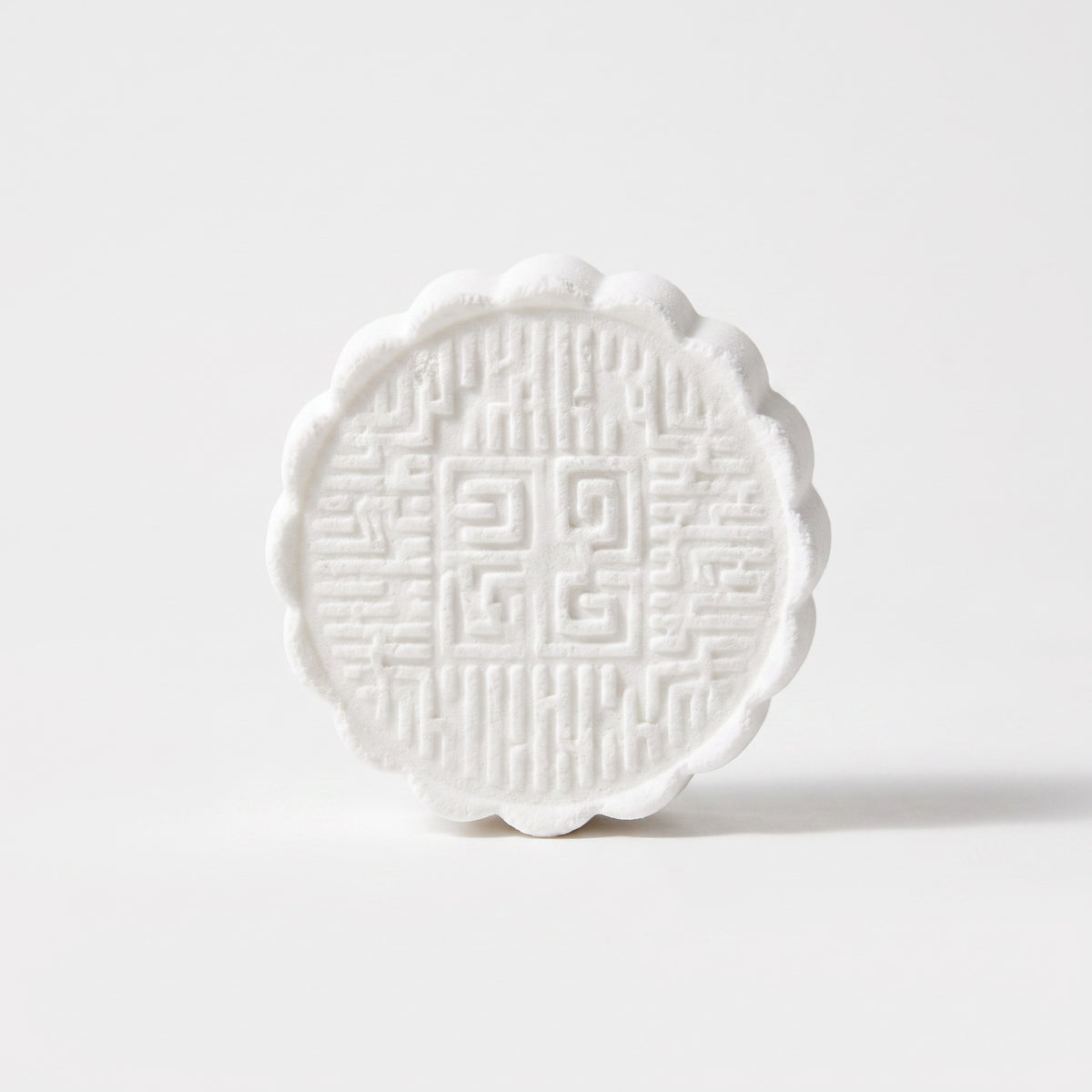 Pure Wash white circular shower steamer with intricate embossed geometric patterns and scalloped edges