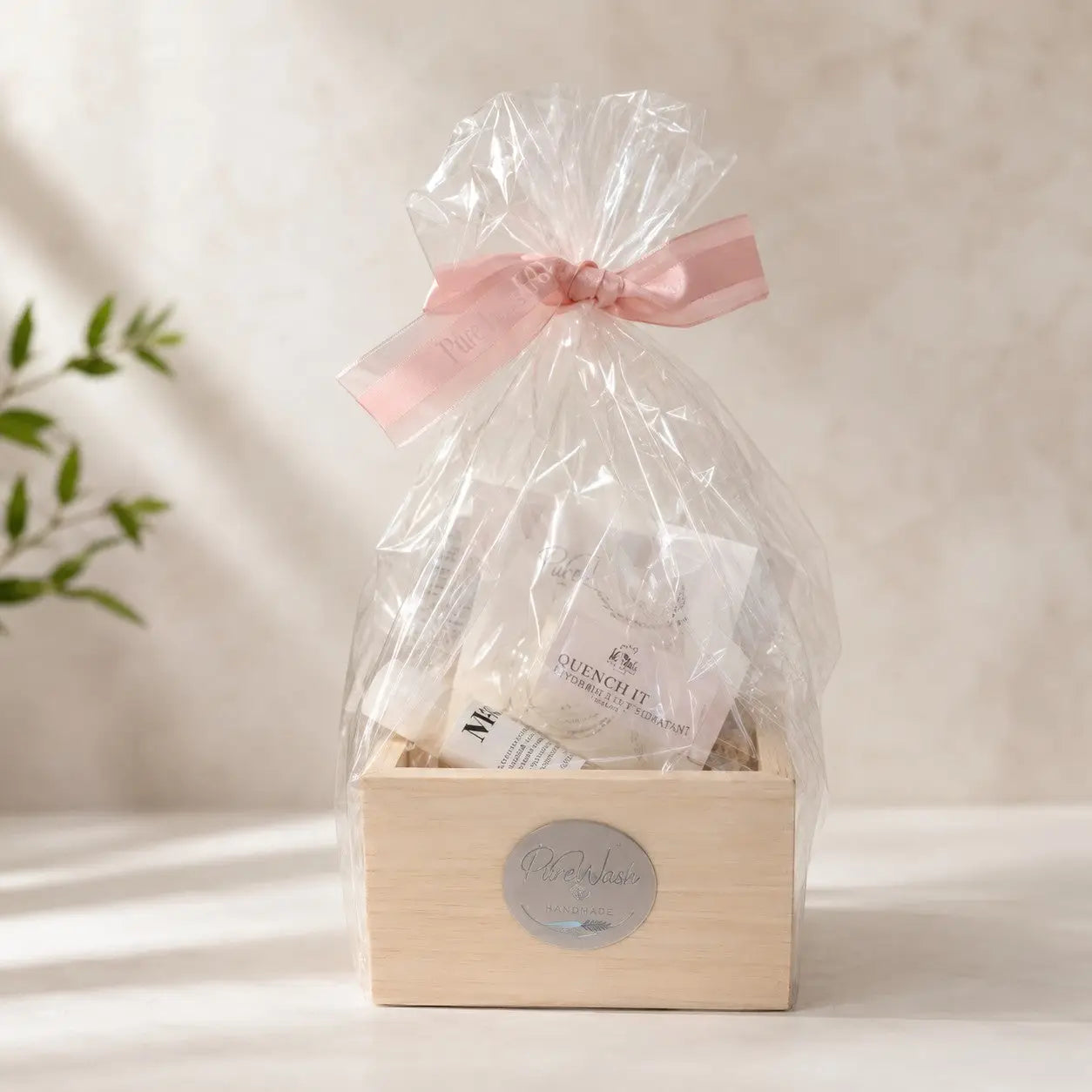 A delicate pink satin ribbon bow on clear cellophane wrapping a wooden natural skincare gift box with exfoliation bar