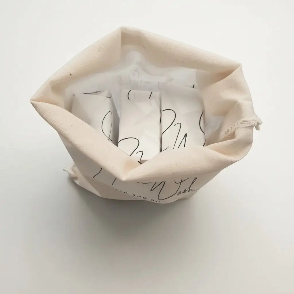 Beige cotton canvas drawstring laundry bag with black cursive lettering for soap trio botanical soap bars packaging