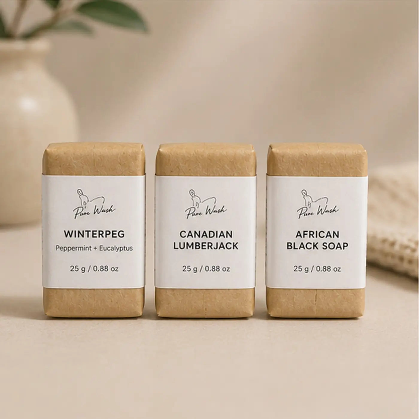 Three rectangular pure wash travel mini soap bars wrapped in brown kraft paper with white labels showing brand and scents