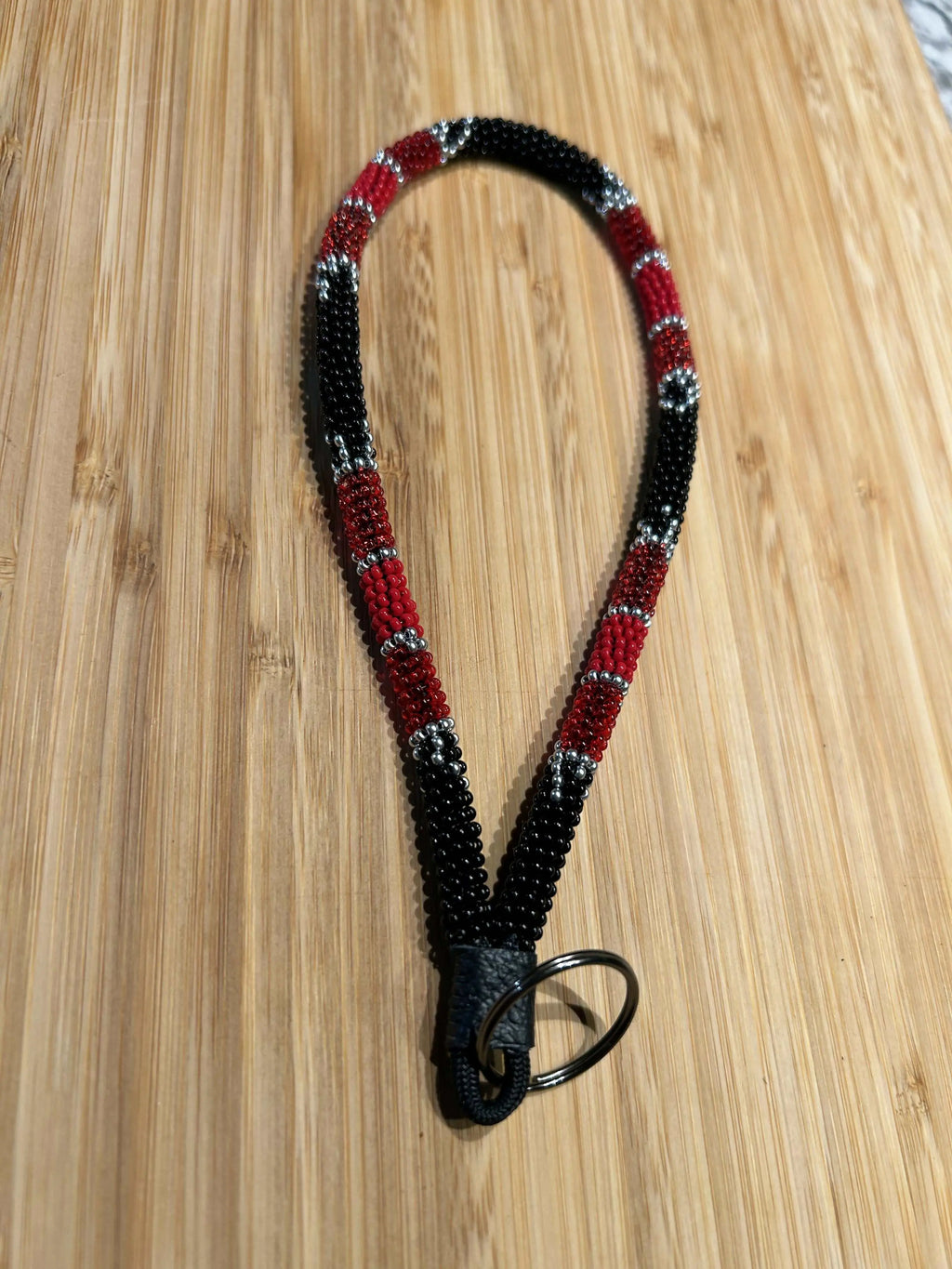 KHAOS Beaded Wristlet Keychain with bright colors and silver accents on a black background, 8” length, leather key ring attachment.