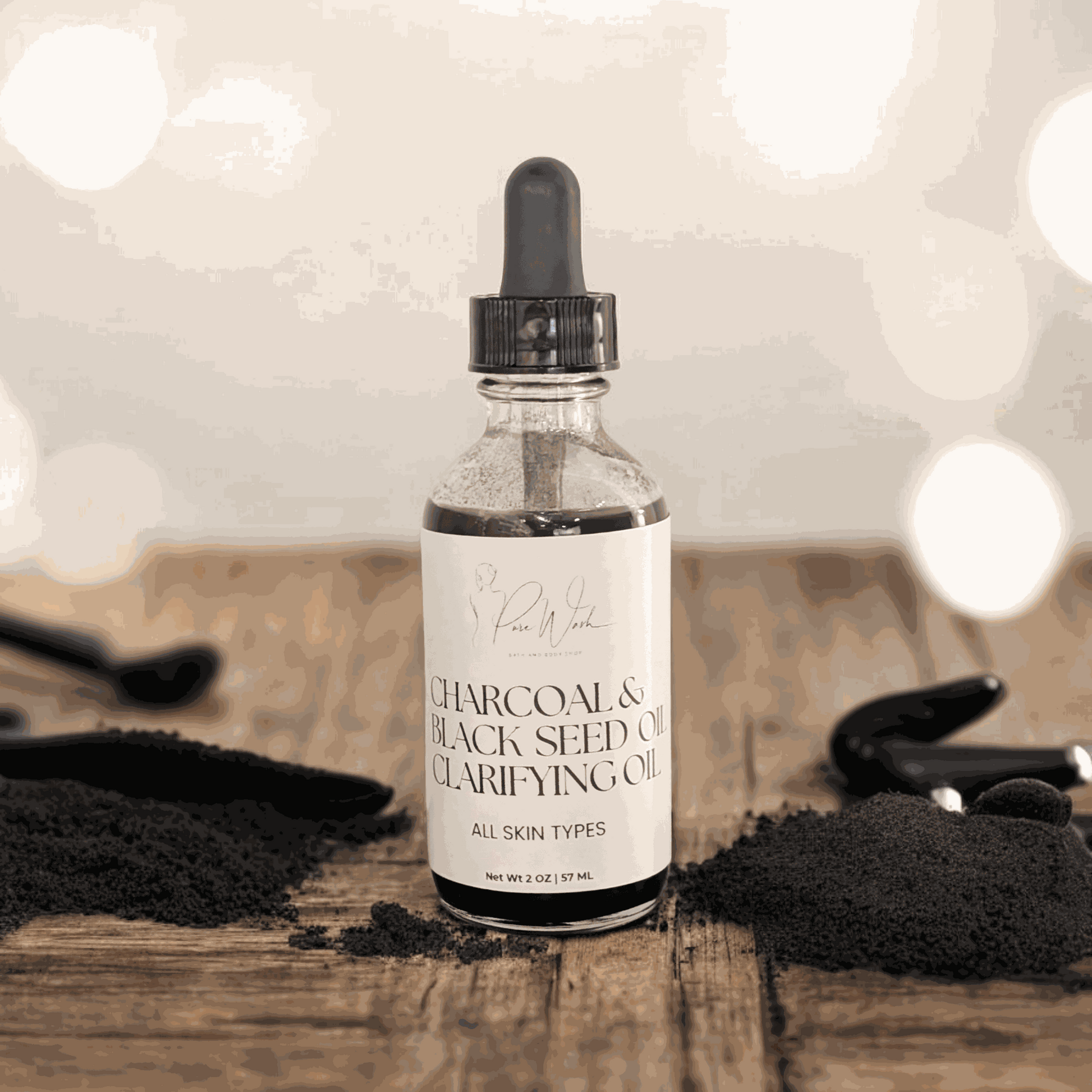 Charcoal & Black Seed Clarifying Oil bottle on wooden surface with charcoal powder.