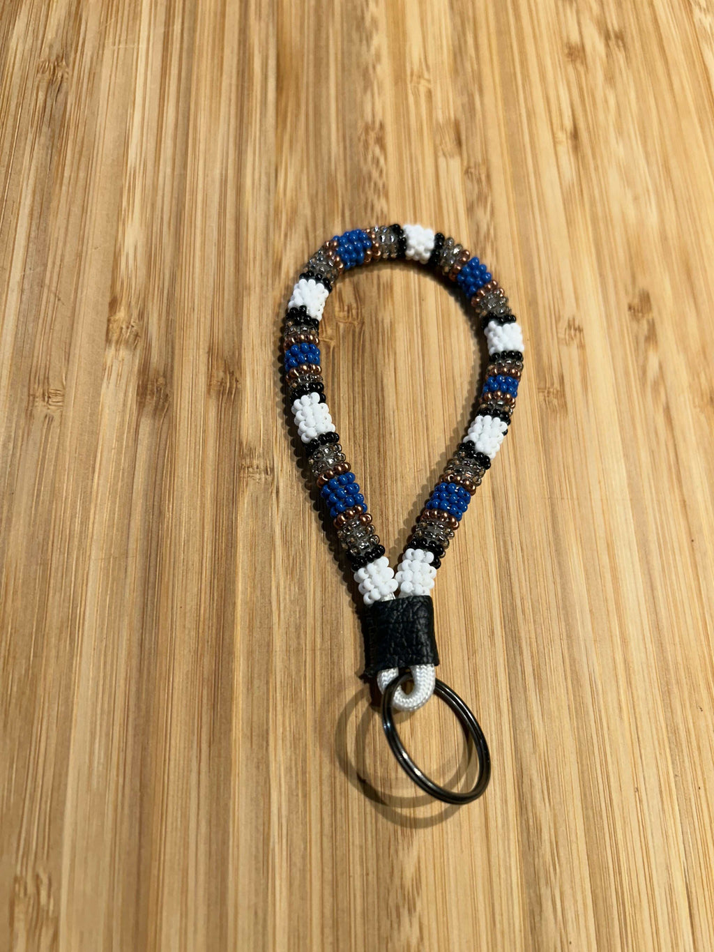 HERA Beaded Mini Keychain with leather and key ring on wooden surface