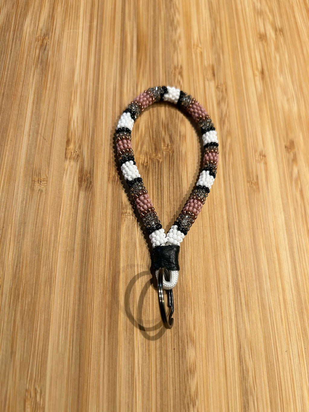 HERA Beaded Mini Keychain with leather and key ring on wooden surface