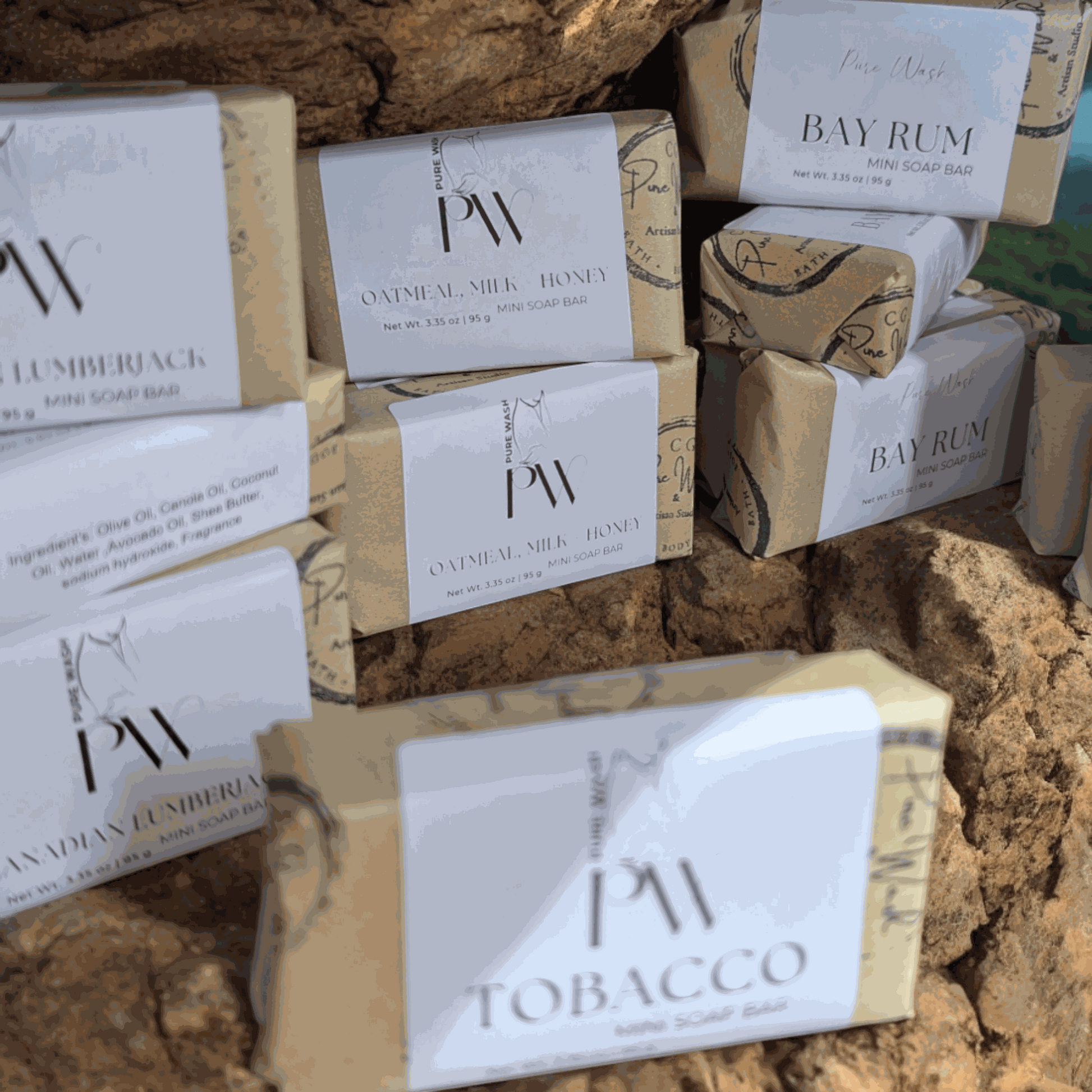 Mini soap bars displayed on natural rocks with various scents like Bay Rum and Tobacco, showcasing eco-friendly packaging.