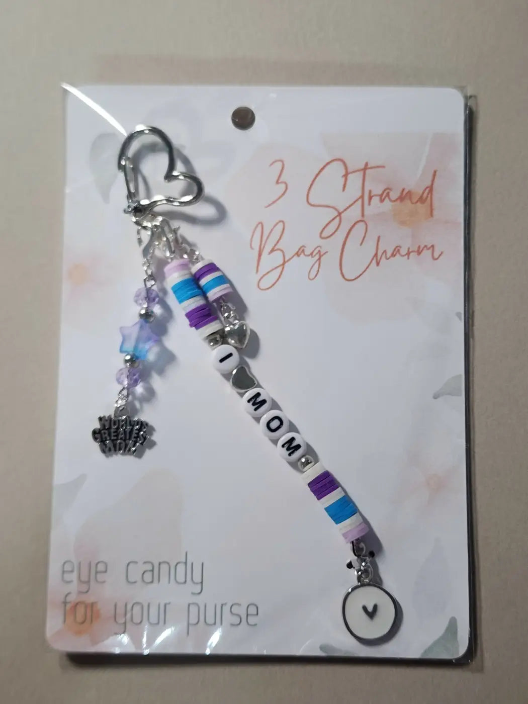 A silver heart clip attaches to a purple blue and white beaded handmade bag charm with i mom letter beads Canadian made skincare
