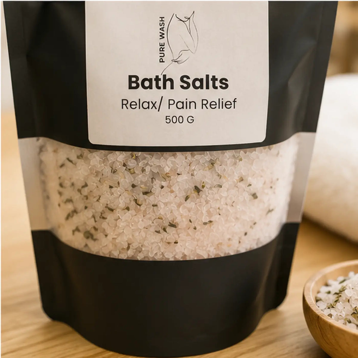 Black pouch of Pure Wash bath salts with clear windows showing white crystals and green botanicals.