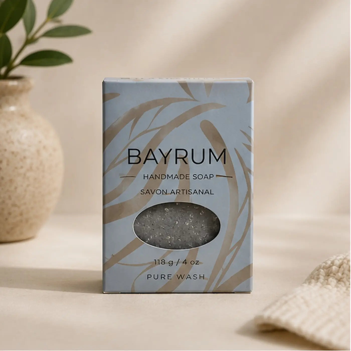 Bay rum soap bar in a light blue box with gold leaf patterns showing a gray sodium shea butterate bar inside