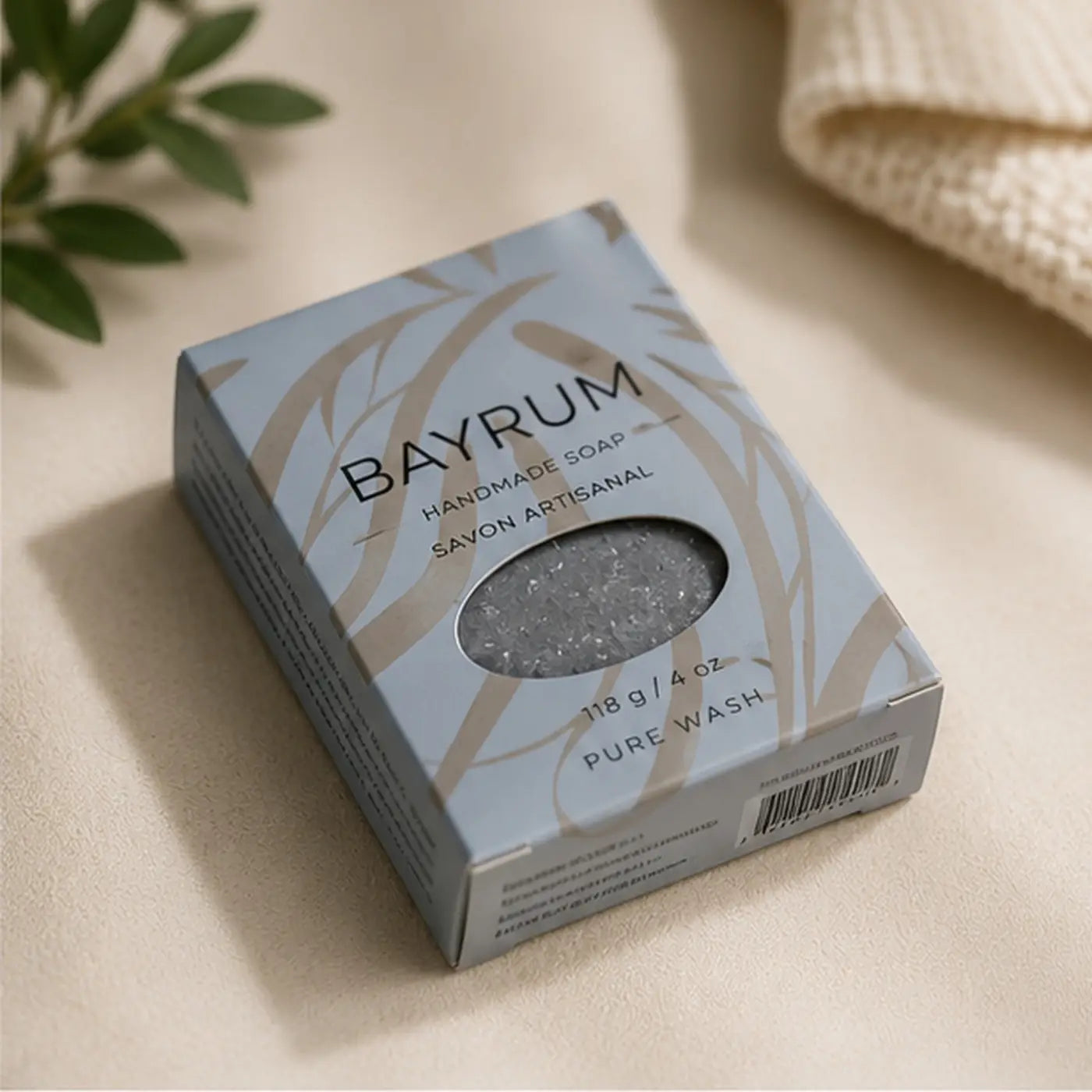 Bay rum soap bar in light blue and beige patterned box with clear window showing gray textured sodium shea butterate bar
