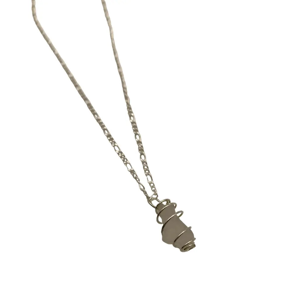 Silver wire-wrapped green beach glass pendant on a delicate chain, laid flat.