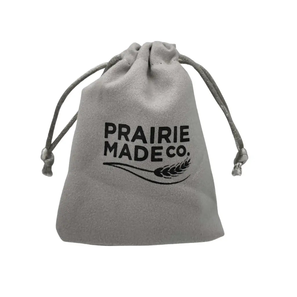 Gray velvet drawstring pouch with black prairie made co logo and wheat graphic for beach glass caged pendant