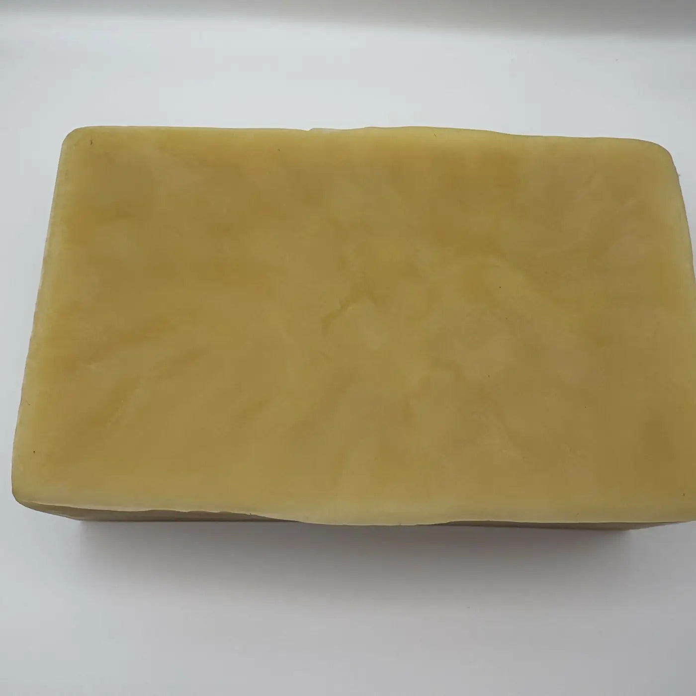A rectangular solid block of hand poured pharmaceutical grade beeswax in pale yellow with a smooth textured surface
