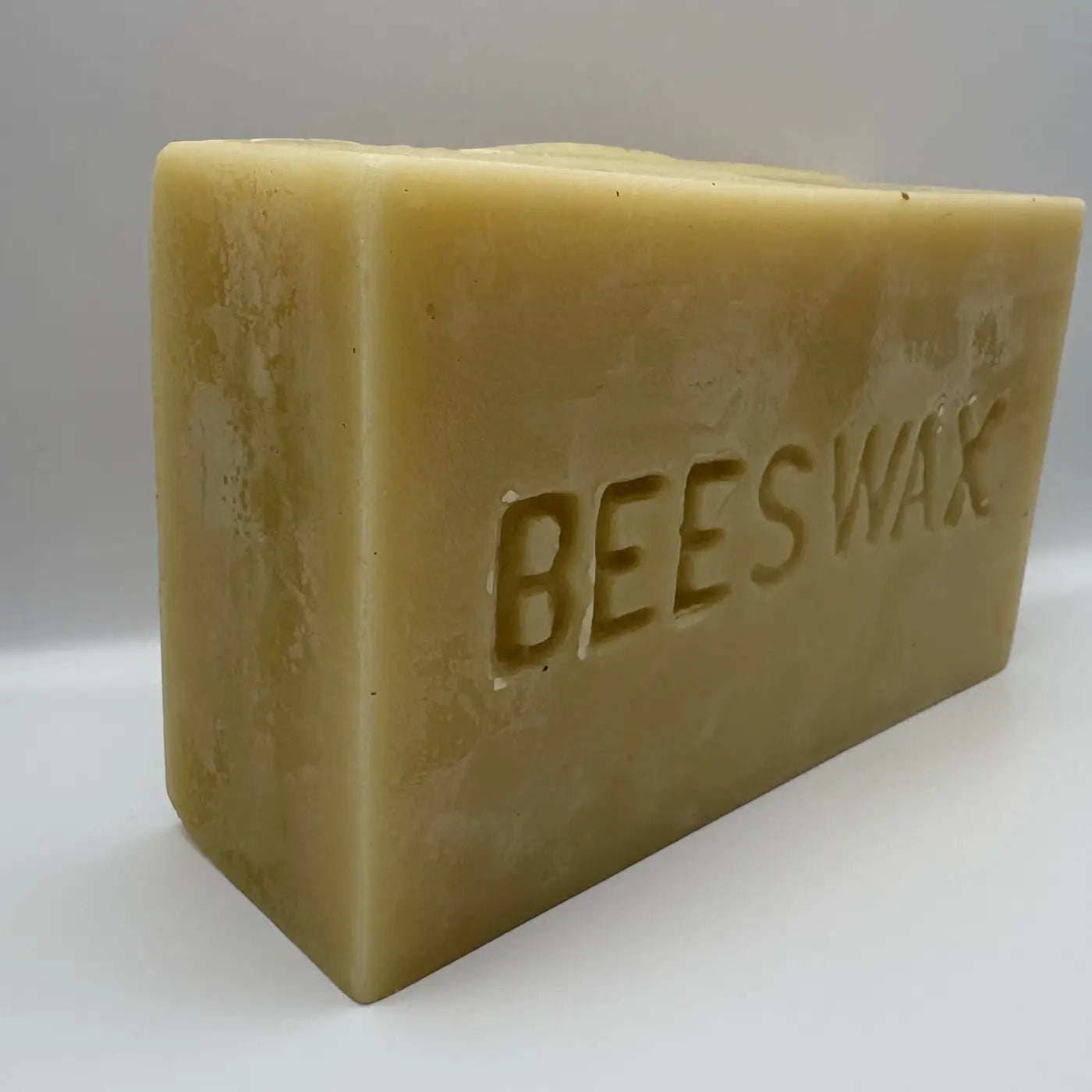 A hand poured pale yellow solid beeswax soap bar embossed with bees wax made from pharmaceutical grade beeswax
