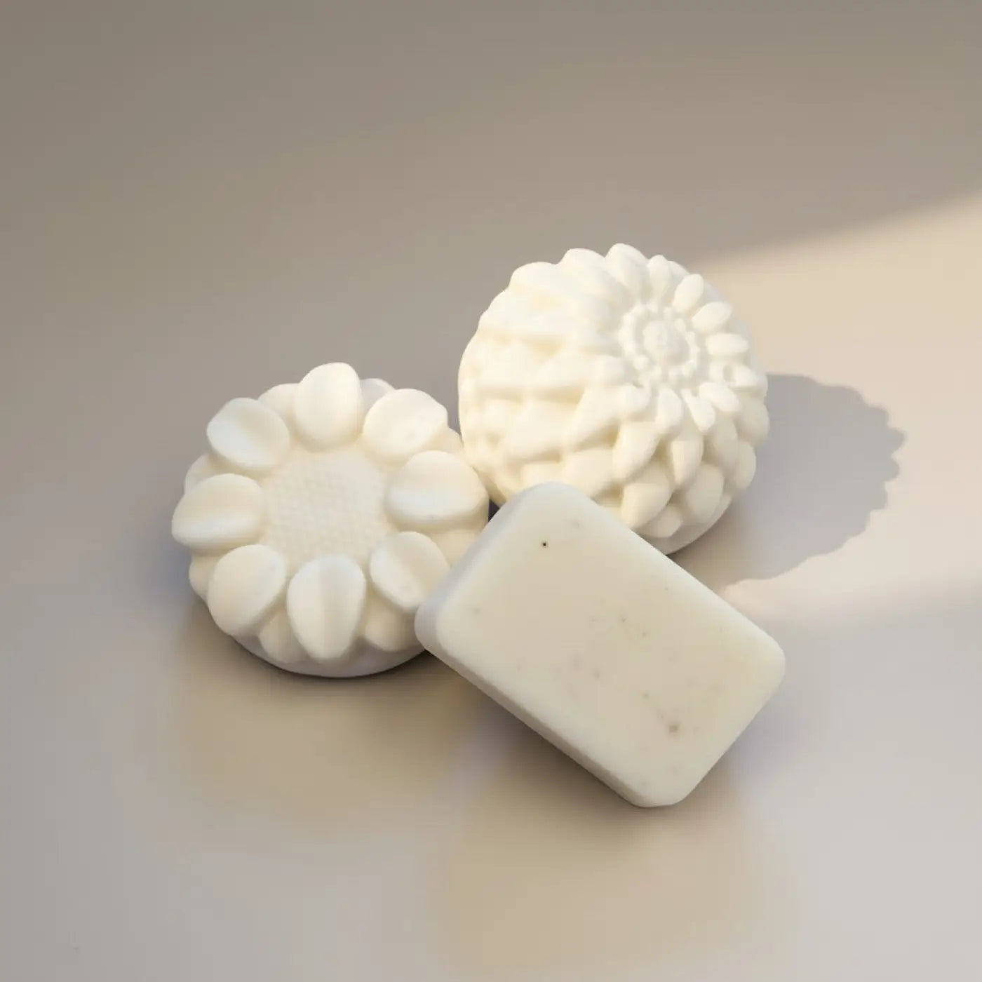 Pure Wash white solid body lotion bars, one rectangular and two floral-shaped, for moisturizing dry skin.