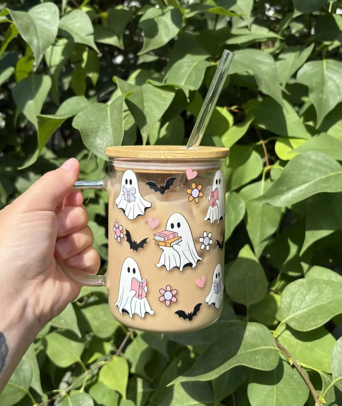 A clear glass bookish ghost mug with a bamboo lid and handle featuring white ghost, hearts, bats, and pastel flowers