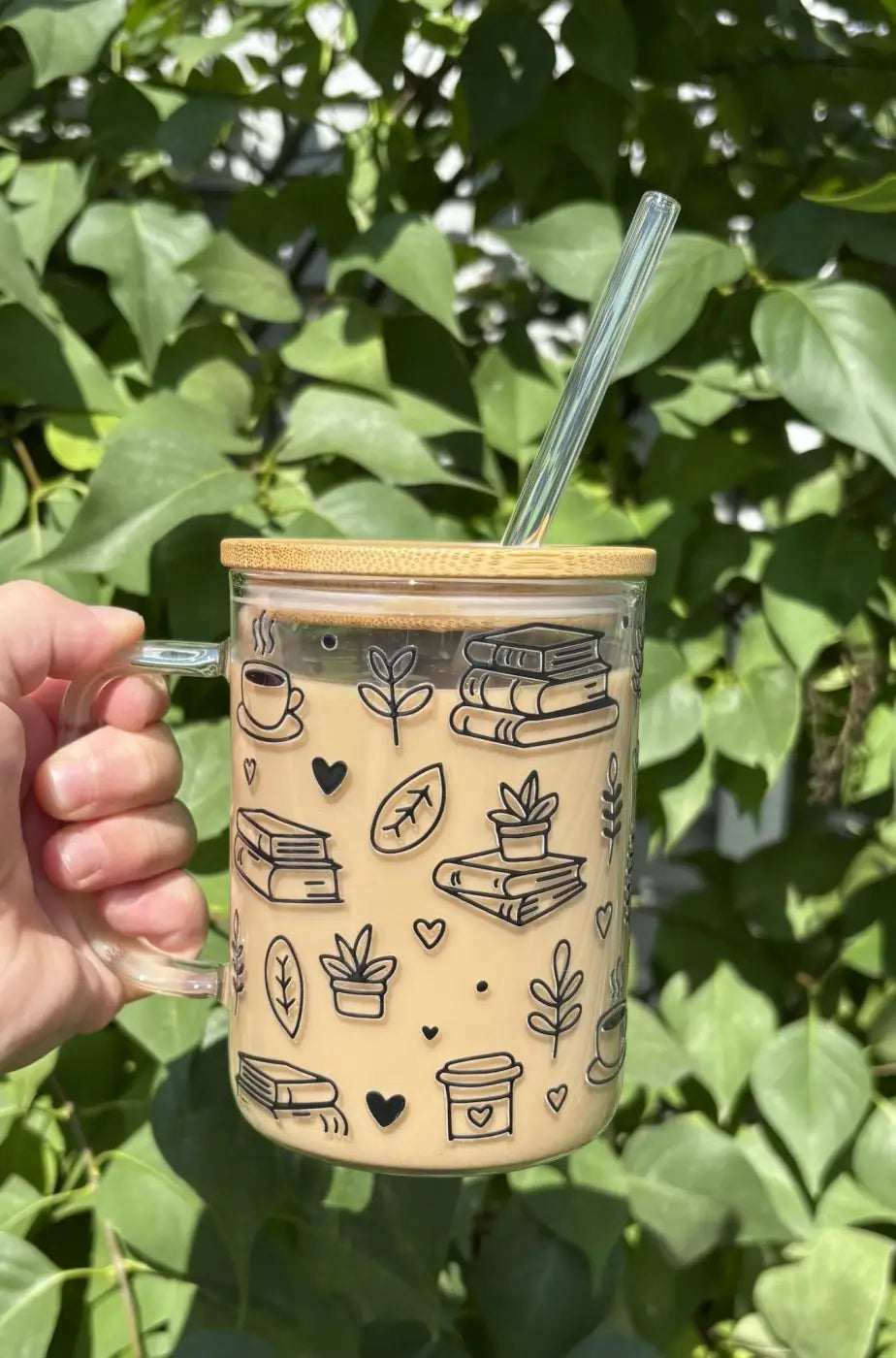 Clear glass bookish glass mug with beige interior black line art and bamboo lid for mug and glass straw for drinking