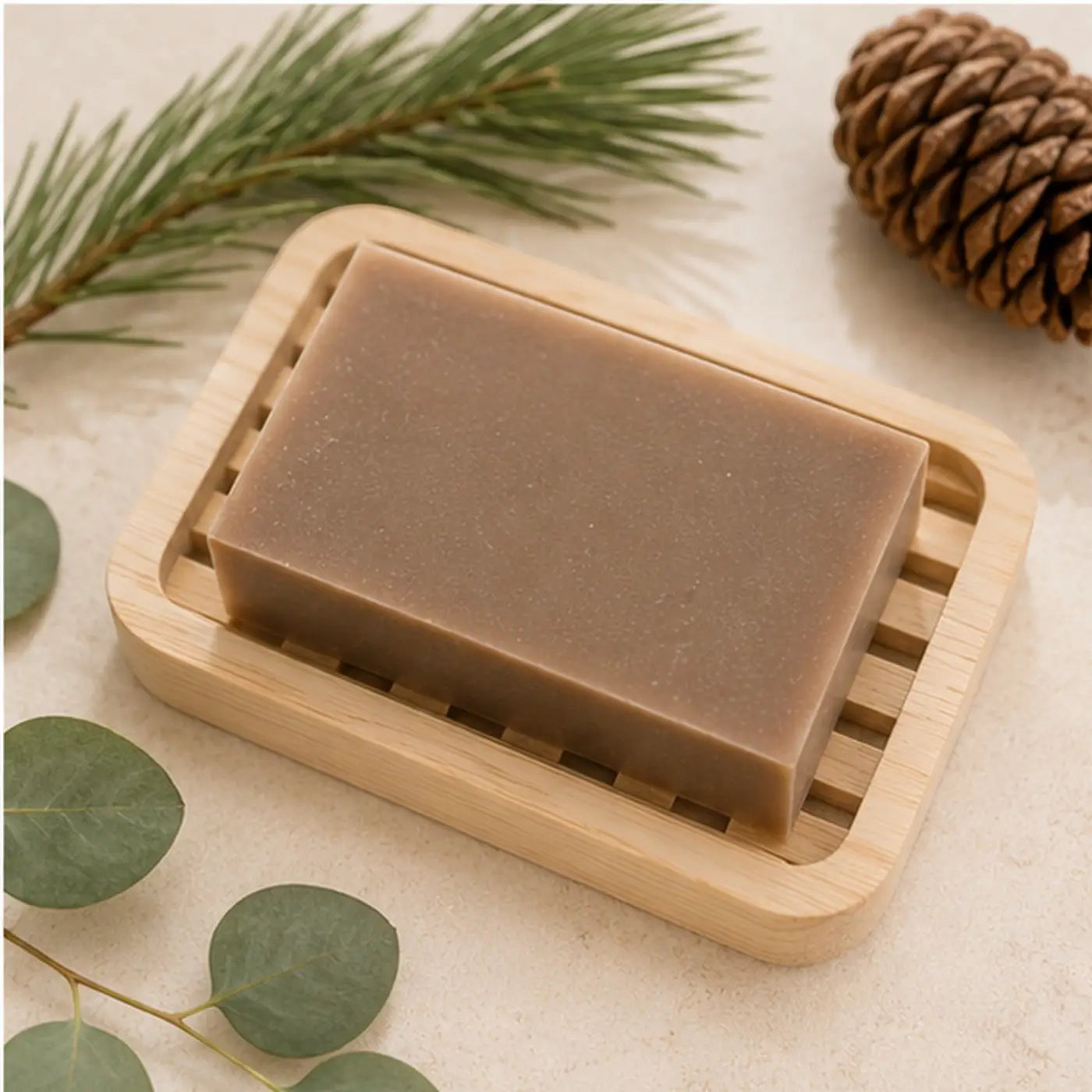 A rectangular earthy brown canadian lumberjack soap bar rests in a light wooden dish for handcrafted skincare