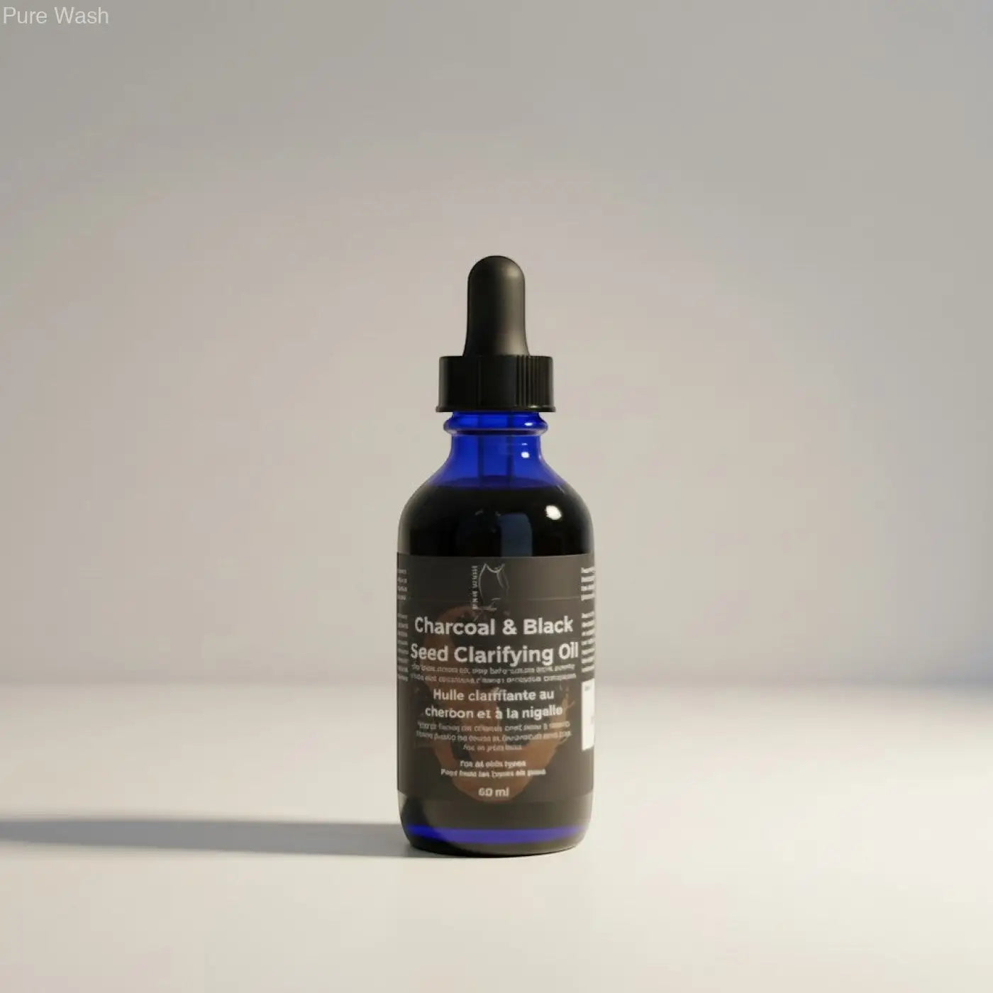 A sleek blue glass bottle with black dropper cap labeled charcoal and black seed clarifying oil by Pure Wash balances sebum production