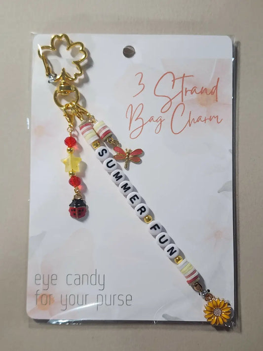 Gold-colored four-leaf clover bag charm with dangling dragonfly, ladybug, and sunflower beads perfect for direct sunlight decor