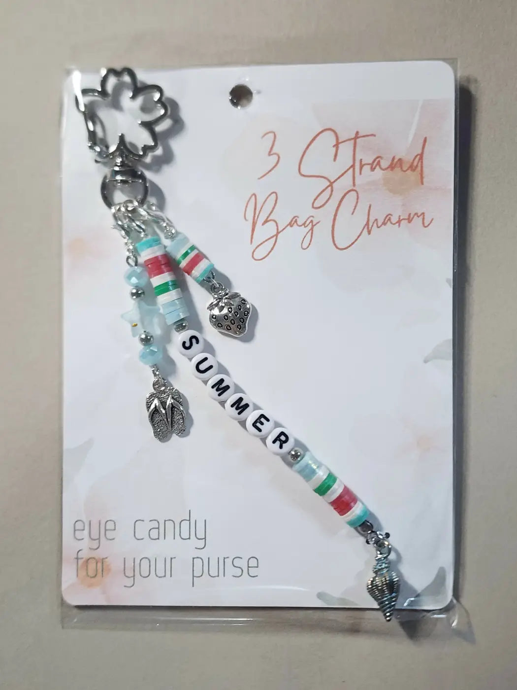 Charm 9 is a silver-toned three-strand bag charm with striped beads, a strawberry pendant, and summer letter charms
