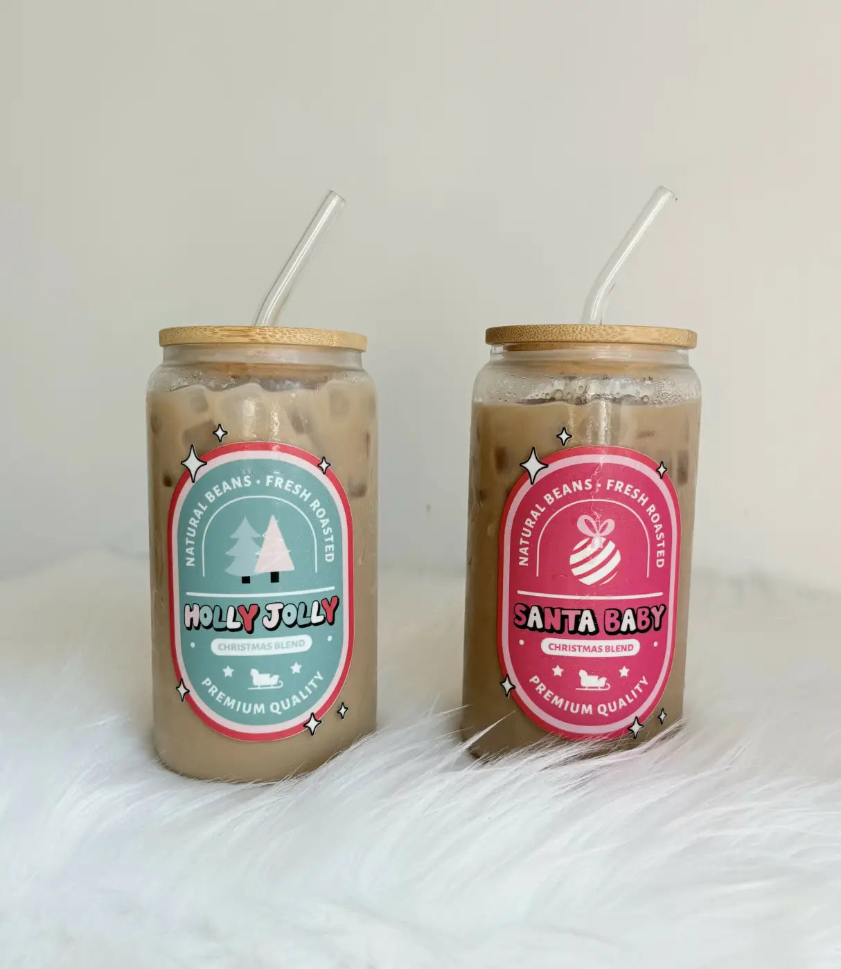 Two festive christmas coffee label cups with stylish bamboo lids, reusable glass straws, and dtf decals in teal and pink