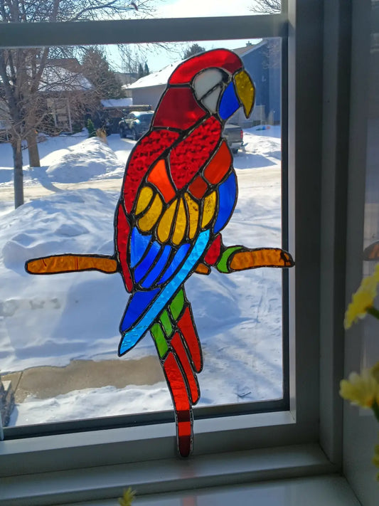 Colorful large parrot stained glass macaw with red blue yellow and green segments perched on a branch
