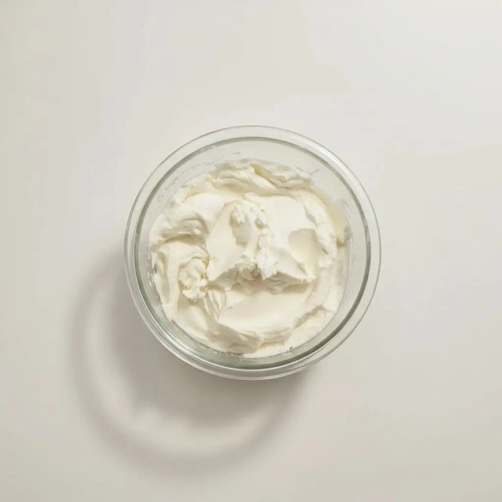 A clear glass bowl filled with creamy white whipped cream for cream it nourishing moisturizer refill only