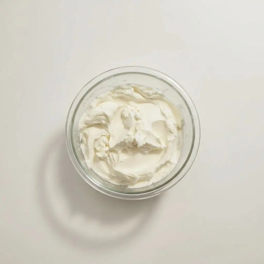 A clear glass bowl filled with creamy white whipped cream for cream it nourishing moisturizer refill only