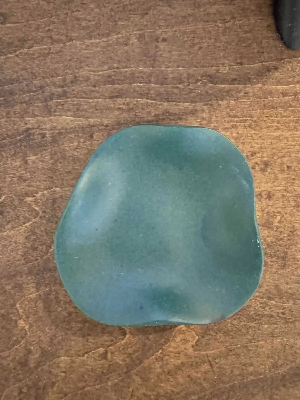 A smooth teal curvy ring holder soap bar with a rounded rectangular shape for convenient ring storage