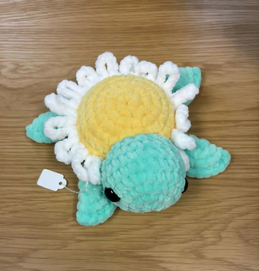 A handmade daisy turtle crocheted plush toy with a yellow shell and teal body ideal for natural skincare canada enthusiasts