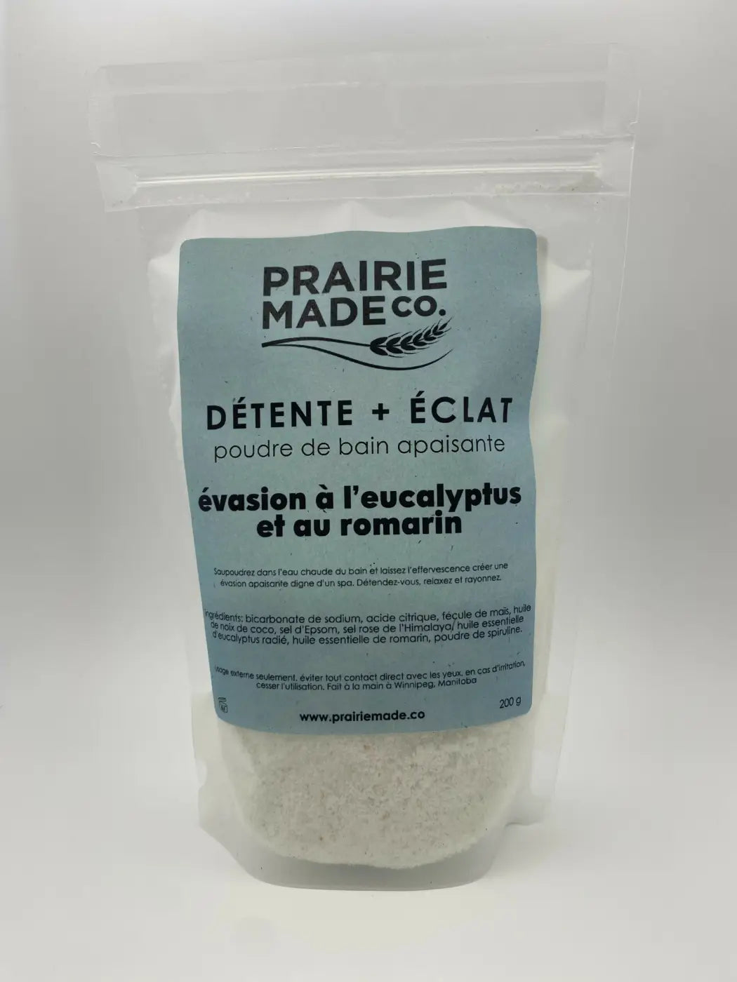 A light blue labeled pouch of prairie made co eucalyptus rosemary fizz calming bath powder with white salts