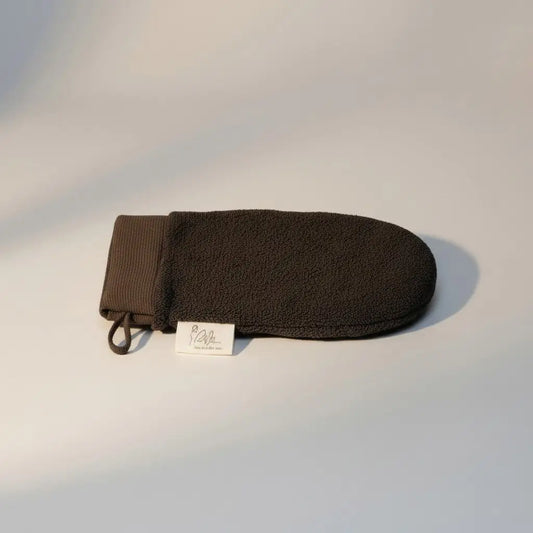 Dark brown exfoliating glove with woven texture and ribbed wristband for effective exfoliation and glowing skin