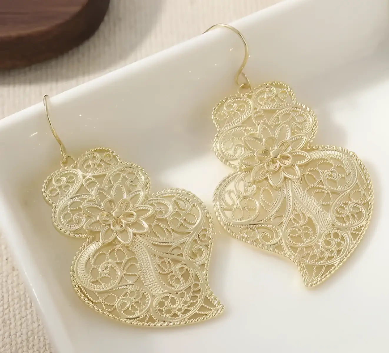 Gold-toned filigree earrings featuring vintage hollow carved heart design with intricate floral lace detailing