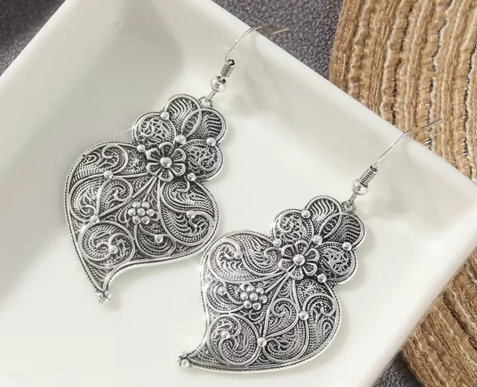 Filigree heart earrings in vintage silvery copper with intricate floral and vine patterns and delicate maxi‑hook style