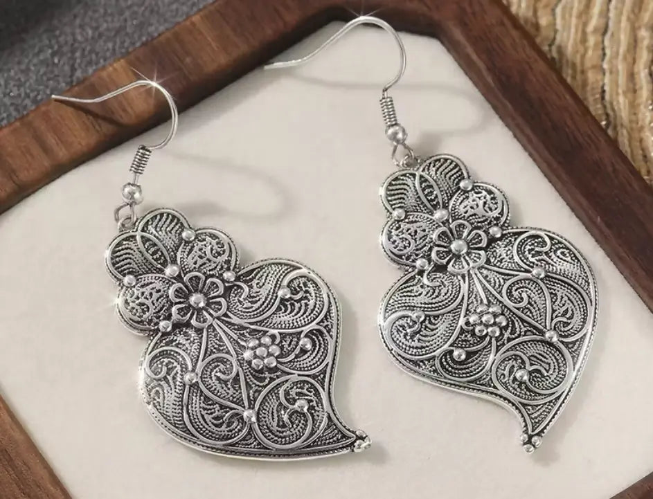 Silver filigree heart earrings with intricate floral swirling patterns and delicate maxi‑hook style in vintage silvery copper