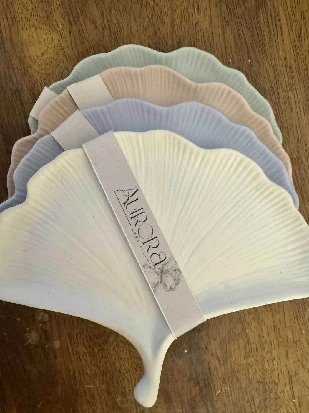 A set of five pastel-colored ceramic fan-shaped coasters with scalloped edges and ribbed texture for gingko tray use