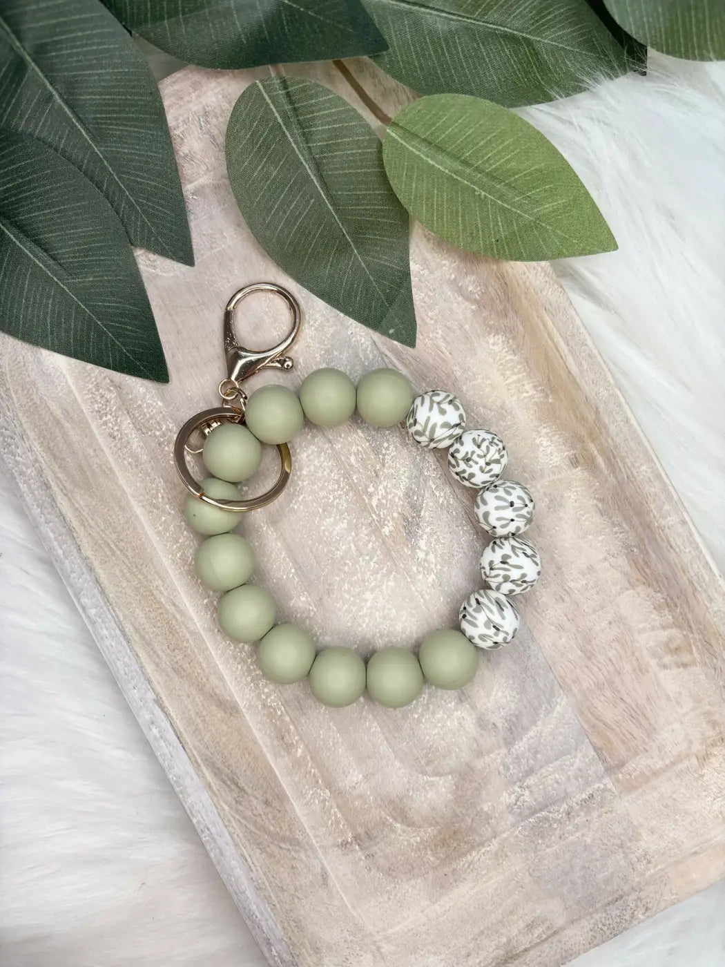 A sage green and white leopard-print floral silicone wristlet keychain with gold-tone clasp perfect earthy floral accessory