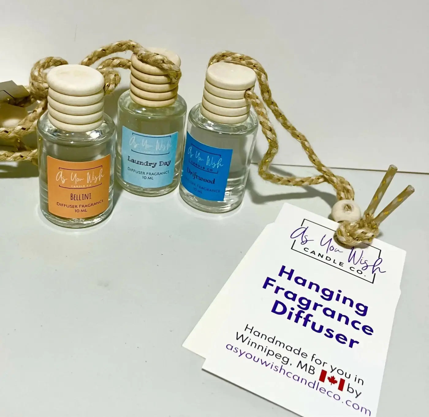 Three clear glass hanging fragrance diffusers with wooden caps and braided rope ties from as you wish candle co