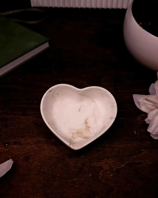A white heart-shaped ceramic heart ring dish with a smooth slightly glossy finish for holding rings