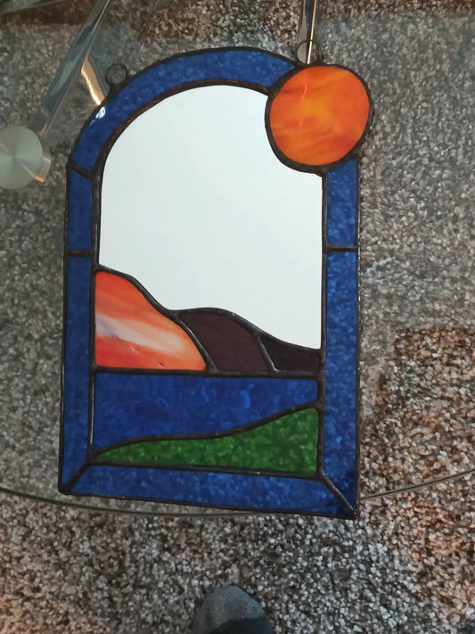 Landscape with sun mirror stained glass panel with arched blue border orange hills and vibrant sun natural skincare canada