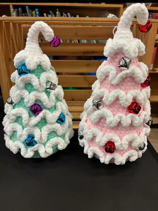 Two large crocheted christmas tree ornaments one mint green with blue bells the other pink with red silver bells