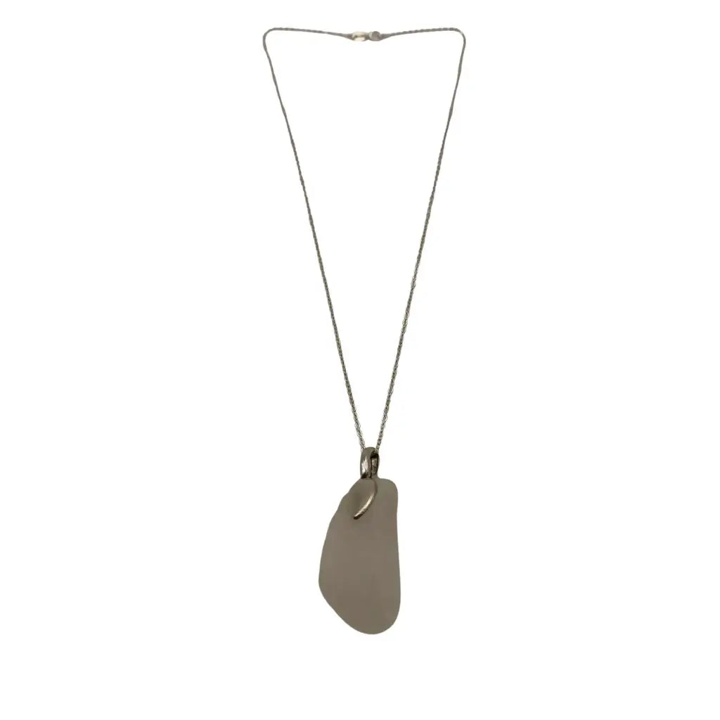 A sleek silver-toned large clear beach glass pendant necklace featuring a smooth translucent beach glass and curved metal accent