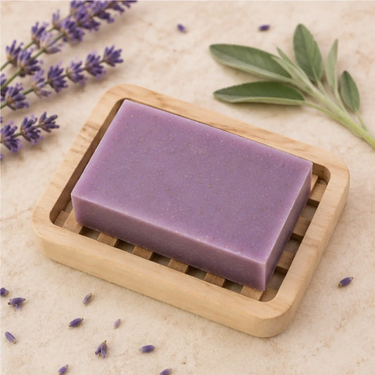 A rectangular solid lavender sage soap bar with clary sage and palm oil rests in a light wood slatted soap dish