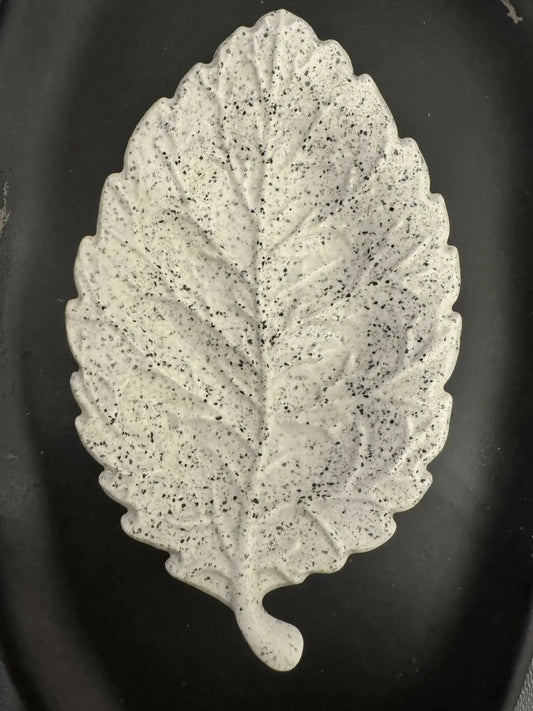 A white speckled ceramic leaf soap dish with textured surface and detailed vein patterns for pure wash use